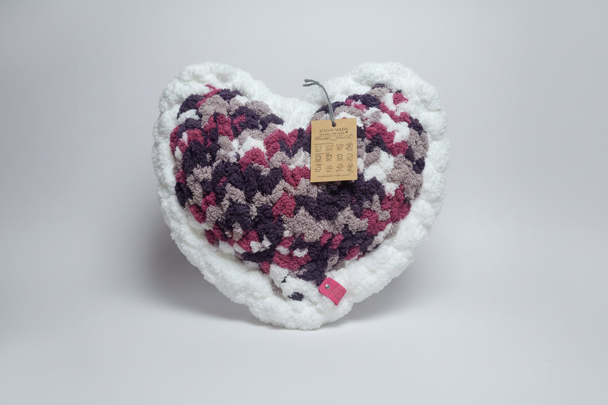 Heart-shaped knitted pillow with a pattern on a white background